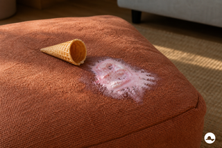 Gesmolten aardbeienroomijs met hoorntje op een terracotta linnen poef