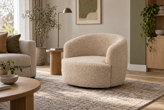 Naturelkleurige Bocca-fauteuil naast een bank en houten bijzettafel in een lichte woonkamer.