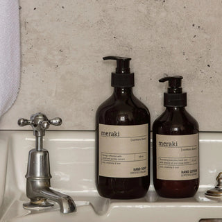 Meraki handzeep en handlotion naast een vintage kraan op een lichte wastafel