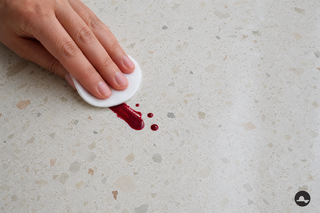 Bordeauxrode nagellakvlek op een lichte terrazzo badkamervloer