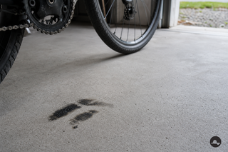 Donkere smeervlek op een lichte betonvloer naast een fiets