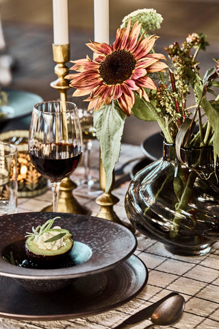 Pion pastabord met avocado op een gedekte tafel met bloemen en kaarsen