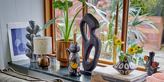 Sfeervol interieur met kleurrijke vazen, kandelaars en sculpturen van Bloomingville