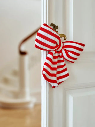 Decoratiestrik rood Ruby 28cm van Bloomingville, hangend aan een deurklink in een licht interieur