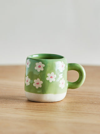 Groene Millie mok met witte bloemen op een houten tafel