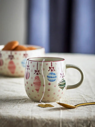 Ornamentia mok met rode kerstornamenten op een gedekte tafel