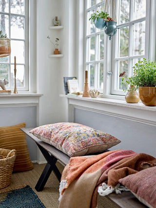 Bruine Ara plaid van Bloomingville gedrapeerd over een bankje in een lichte woonkamer