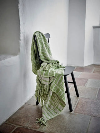 Groene Velva plaid nonchalant over een zwarte stoel