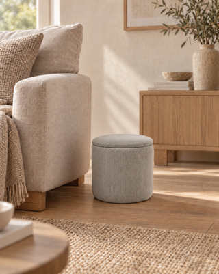 Grijze geribbelde opbergpoef Arth naast een lichte bank in een zonnig interieur