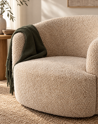 Grove stofstructuur van de Bocca-fauteuil met een donkergroene plaid over de armleuning.