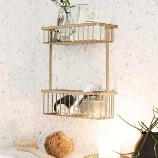 Messingkleurig wandrek met twee draadmanden, gestyled met glazen potten en badkameraccessoires