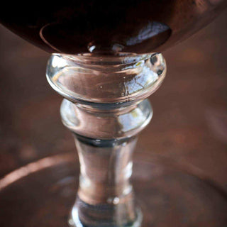 Detail van de gedecoreerde steel van een helder bierglas, gevuld met donker bier