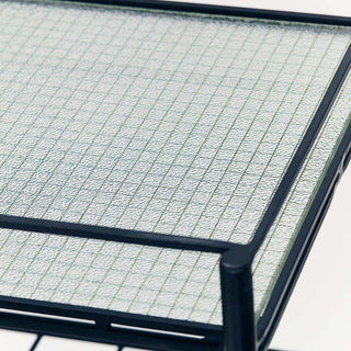 Detail van bijzettafel Gany met geribbeld glazen blad en slank donker frame
