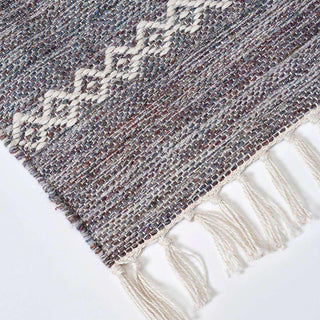 Detail van buitenkleed Ciero met gemêleerde weving, geometrisch motief en geknoopte franjes