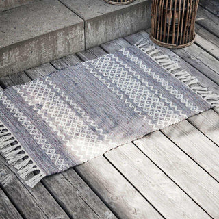 Buitenkleed Ciero met geometrisch patroon en franjes op een verweerd houten terras