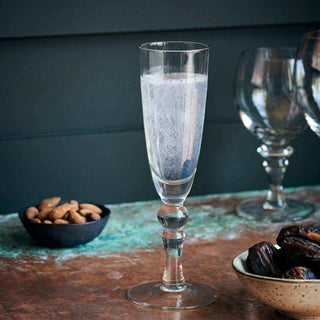 Helder champagneglas met drank op een tafel, naast schaaltjes met noten en dadels