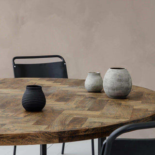 Ronde eettafel Kant met visgraatpatroon, drie vazen en zwarte stoelen