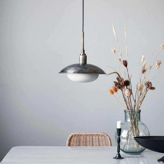 Hanglamp met metalen kap en witte glazen scherm boven eettafel
