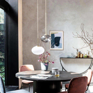 Ronde eettafel met donker houten blad, roze fluwelen stoelen en hanglampen in moderne woonkamer