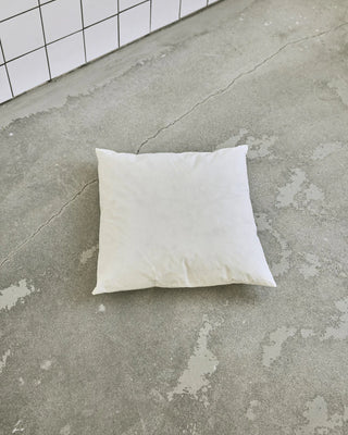Witte kussenvulling van 50 bij 50 cm op een grijze vloer