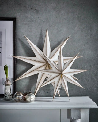Papieren ster 9 punten champagne 45cm van House Doctor, samen met een grotere papieren ster op een kast in het interieur