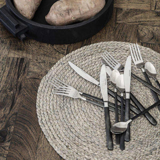Zilveren bestek met zwarte handvatten op rieten placemat