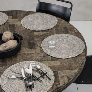 Ronde gevlochten placemats op houten tafel met bestek en glas