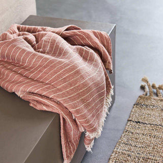 Gestreept Dusty Berry plaid met franjes los gedrapeerd over een lage kast