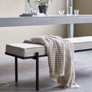 Gestreept plaid met franjes over een gestoffeerde bank in een rustig interieur