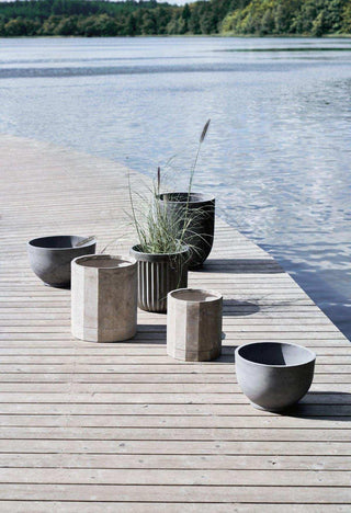Ronde Gard plantenpotten tussen andere potten op een houten steiger aan het water
