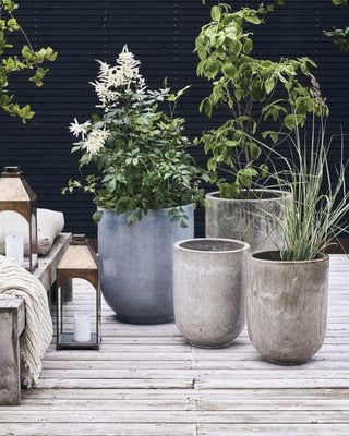Twee Pot Pho bloempotten, één leeg en één met siergras, op een houten terras