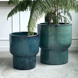 Twee groenblauwe bloempotten van verschillend formaat met groene planten