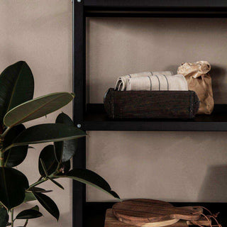 House Doctor Use rek met opbergkist, gevouwen doeken en kamerplant in een interieur