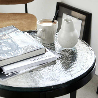 Salontafel Smoke met reliëfglazen blad, boeken, mok en kleine kan in een zithoek