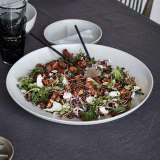 House Doctor Pion serveerschaal gevuld met salade en serveerbestek op een gedekte tafel