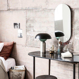 Sidetable Eda met donker geaderd blad, lamp en spiegel naast een bed