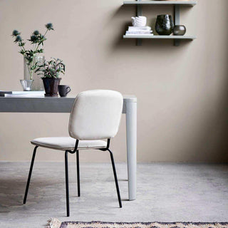 Stoel Coton met zandkleurige bekleding en zwart onderstel bij een tafel met planten en servies