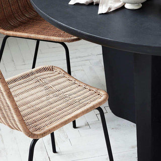Twee stoelen Haput met gevlochten zittingen en zwarte poten naast een ronde tafel