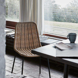 Stoel Haput aan een tafel bij een groot raam, met boeken en een mok in de setting