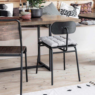 Donkerbruine stoel met grijs zitkussen aan een houten eettafel in een ingerichte eetruimte