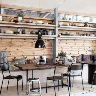 Stoel Original met donkere zitting aan een houten tafel in een rustieke eethoek met wandplanken