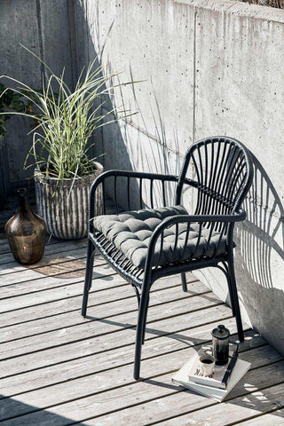 Brea tuinstoel met gecapitonneerd zitkussen op een houten terras naast een plantenpot
