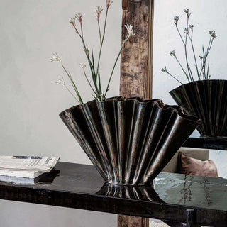 Geplooide Flood vaas met hoge bloemstelen op een glanzende tafel voor een spiegel