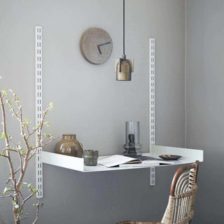 Lichtgrijs wandbureau Fari aan de muur met open boek, vazen, hanglamp en stoel