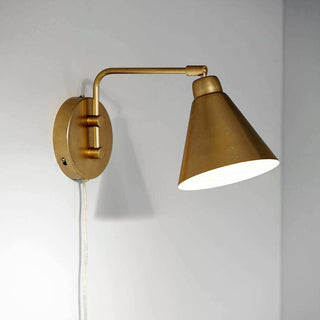 Messing wandlamp Game aan een lichte muur, met gebogen arm, gekantelde kap en zichtbaar snoer