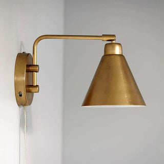 Zijaanzicht van messing wandlamp Game aan de muur, met lange gebogen arm, conische kap en snoer