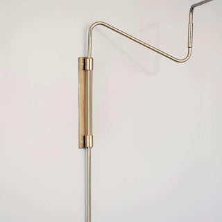 Detail van de messing wandbevestiging en gebogen arm van de Swing wandlamp