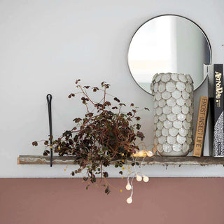 Ronde spiegel en schelpenvaas op houten plank met plant en boeken