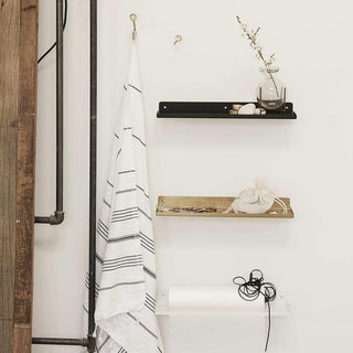Zwarte, goudkleurige en witte wandplanken met decoraties en handdoek in industrieel interieur