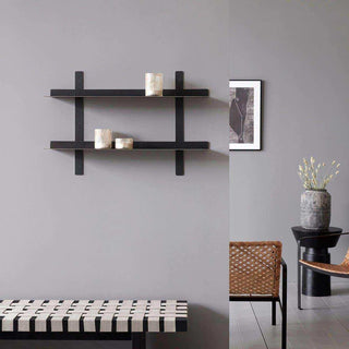 Zwart wandrek met twee planken aan een grijze muur, gestyled met kleine decoratieve objecten